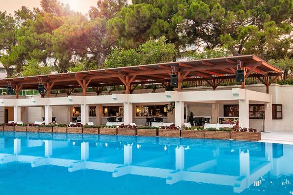 Poolbereich des Rixos Premium Tekirova Hotels mit überdachter Terrasse und umliegenden Bäumen