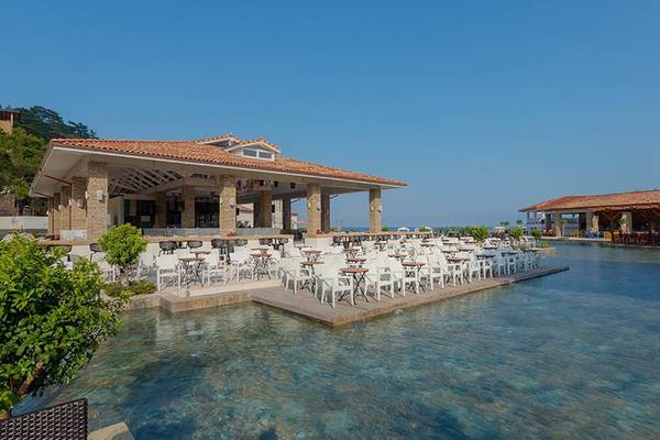 Außenterrasse des Rixos Premium Tekirova Hotels mit vielen weißen Stühlen und Tischen am Wasser.