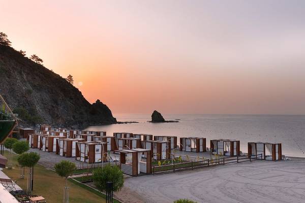 Abendlicher Blick auf das Strand des Rixos Premium Tekirova mit vielen weißen und braunen Strandhütten.