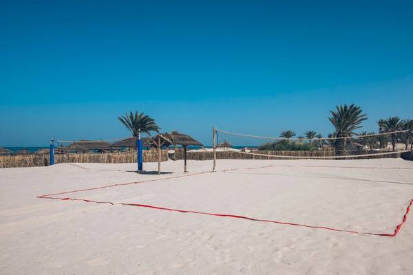 Volleyballfeld im Iberostar Mehari Djerba Hotel, mit Netz und Palmen im Hintergrund.