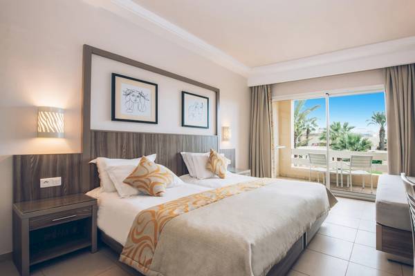 Doppelbettzimmer im Iberostar Mehari Djerba Hotel mit Blick auf den Balkon und Außenbereich.