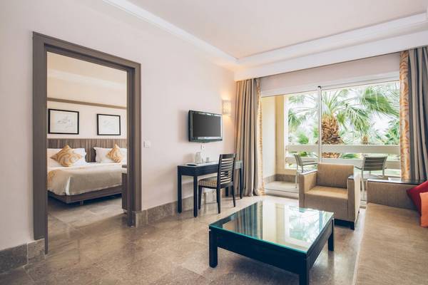 Innenansicht eines Hotelzimmers im Iberostar Mehari Djerba mit Bett, Schreibtisch, Couch und Terrasse.