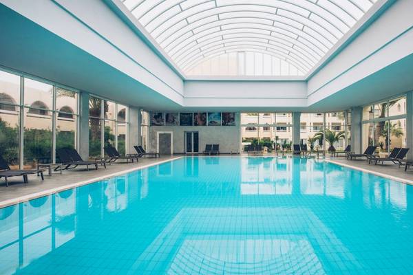 Ein großer Swimmingpool im Iberostar Mehari Djerba Hotel mit Liegestühlen und Glaswänden