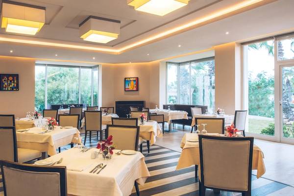 Innenansicht des Restaurants im Iberostar Mehari Djerba Hotel mit gedeckten Tischen und Glaswänden.