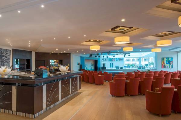 Innenansicht der Bar im Iberostar Mehari Djerba Hotel mit moderner Einrichtung, roten Stühlen und einem langen Tresen.