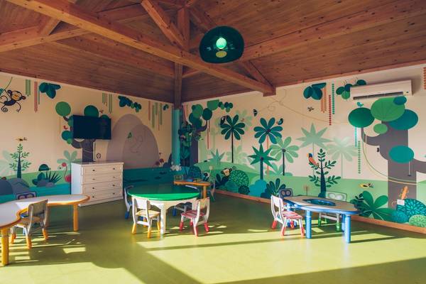 Kinderzimmer im Iberostar Mehari Djerba mit grünen und blauen Möbeln und tropischen Wandmalereien.