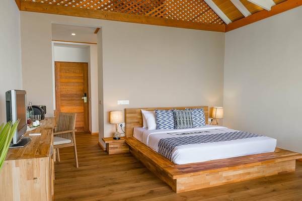 Kudafushi Resort & Spa Hotelzimmer mit Holzbett, Fernseher und Schreibtisch.
