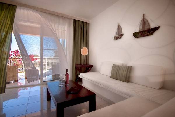 Wohnzimmer mit Couch, Tisch und Blick auf den Balkon im Belvedere Luxury Suites Hotel.