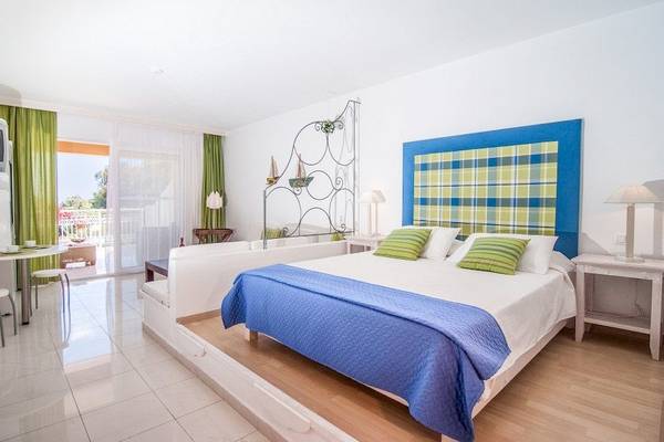 Innenansicht eines Zimmers im Belvedere Luxury Suites mit einem Bett, einem Tisch und einer Terrasse.