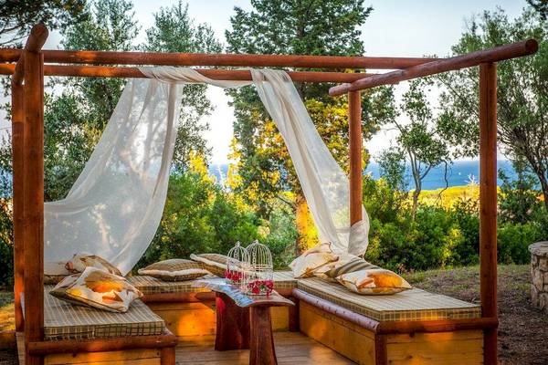 Holzterrasse mit Betten und Vorhängen im Garten des Belvedere Luxury Suites Hotels