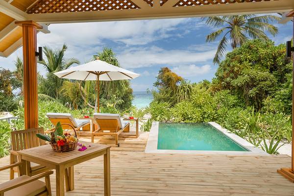 Terrasse im Kudafushi Resort & Spa mit einem Pool und einem geöffneten Regenschirm
