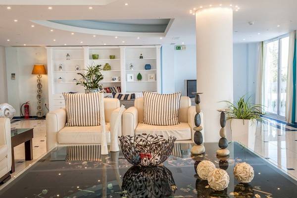 Hotellobby mit weißen Sofas, gemusterten Kissen, und dekorativen Elementen.