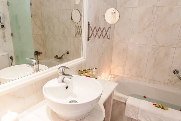 Luxuriöses Badezimmer der Belvedere Luxury Suites mit Badewanne, Waschbecken und Spiegel.