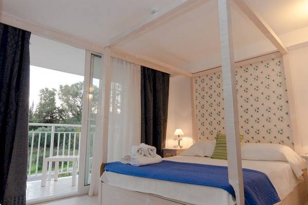 Schlafzimmer mit Balkon im Belvedere Luxury Suites Hotel, mit vierpfosten Bett, Blick auf den Garten.