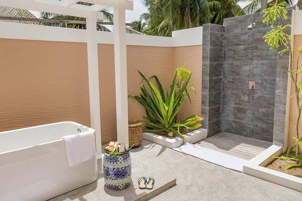 Badezimmer im Kudafushi Resort & Spa mit Badewanne, Dusche und Pflanzen.