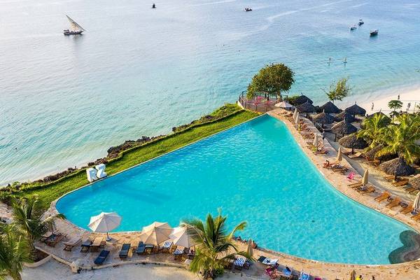 Luftaufnahme des Pools und der Sonnenliegen des Royal Zanzibar Beach Resort mit Blick auf das Meer.