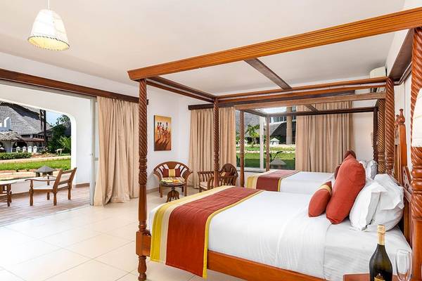 Schlafzimmer im Royal Zanzibar Beach Resort mit zwei Himmelbetten, Blick auf den Garten.