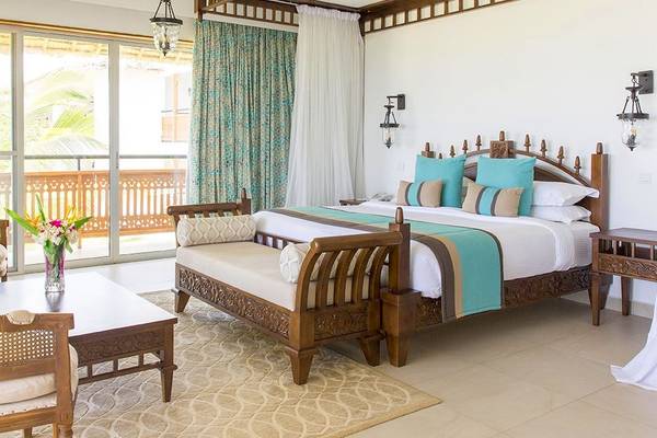 Schlafzimmer im Royal Zanzibar Beach Resort mit einem großen Bett, einem Sofa und einem Tisch.