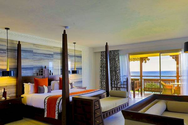 Schlafzimmer im Royal Zanzibar Beach Resort mit Meerblick, einem großen Bett, Nachttischen und einem Balkon.