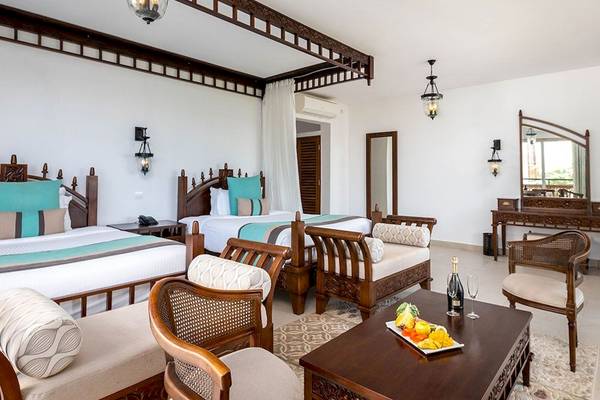 Innenansicht einer Suite im Royal Zanzibar Beach Resort mit zwei Betten und Wohnzimmermöbeln.