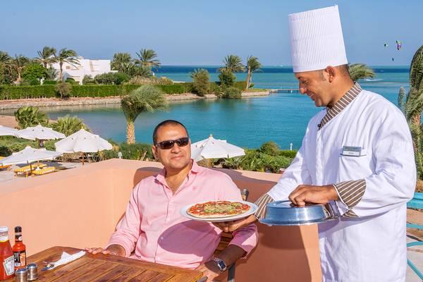 Koch serviert Pizza auf der Terrasse mit Blick auf das Meer im Chedi El Gouna