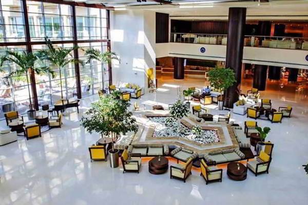 Lobby des Rixos The Palm Hotel & Suites mit zentralem Brunnen, Sitzbereichen und Pflanzen.