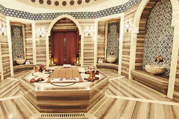 Innenansicht des Spas im Rixos The Palm Hotel & Suites mit Marmorwänden und einem zentralen Bad.