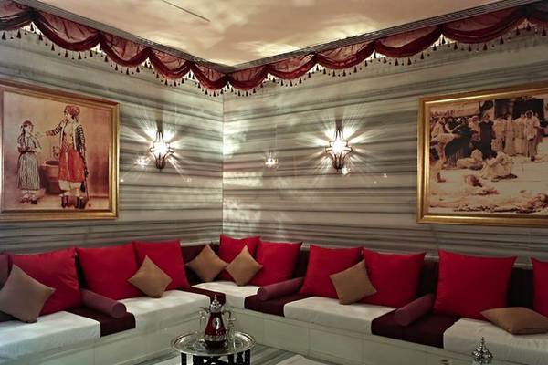 Innenbereich des Rixos The Palm Hotel & Suites mit einem weißen Sofa, roten Kissen und zwei Gemälden an der Wand.