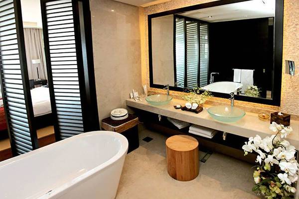 Badezimmer im Rixos The Palm Hotel & Suites mit Badewanne, Waschbecken und Spiegel.