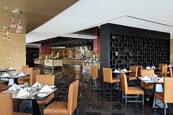 Innenansicht des Restaurants im Rixos The Palm Hotel & Suites mit gedeckten Tischen und Stühlen.