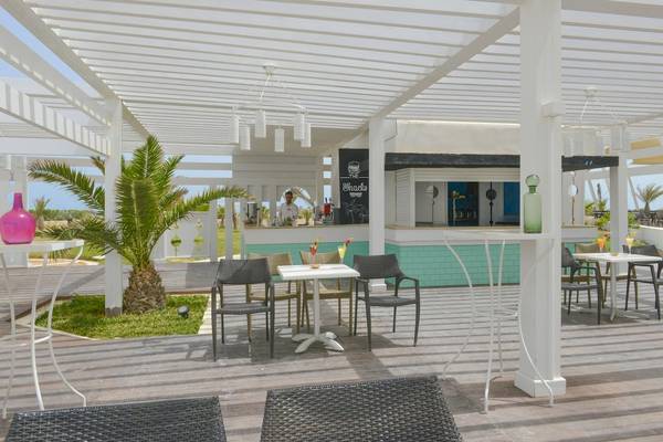 Terrasse des Vincci Helios Beach Hotels mit Tischen, Stühlen und einer Bar.