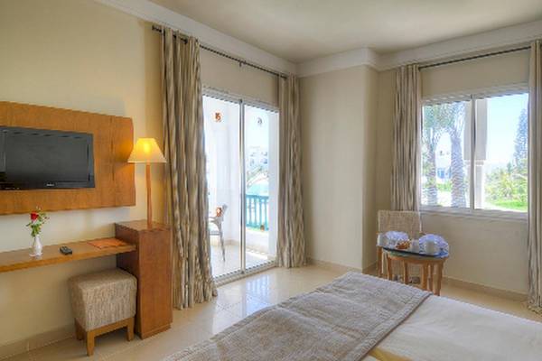 Doppelzimmer mit Balkon im Vincci Helios Beach Hotel, inklusive Fernseher, Schreibtisch, bequemen Betten und Blick auf den Garten.