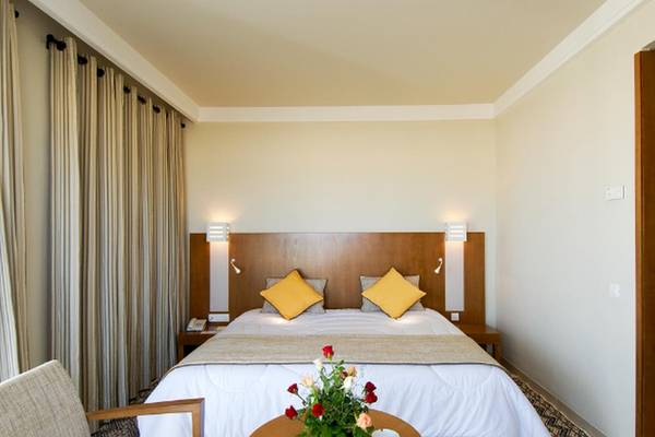 Schlafzimmer im Vincci Helios Beach Hotel mit zwei gelben Kissen und Blumen auf dem Tisch.