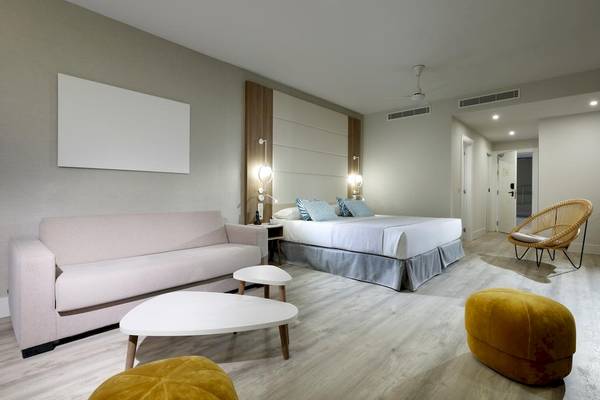 Schlafzimmereinrichtung im Playabonita Hotel mit Bett, Sofa, Tischen und Stühlen.