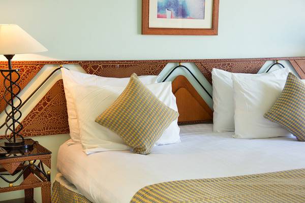 Ein luxuriöses Hotelbett im Chedi El Gouna mit weißen und blau-gelben Kissen.
