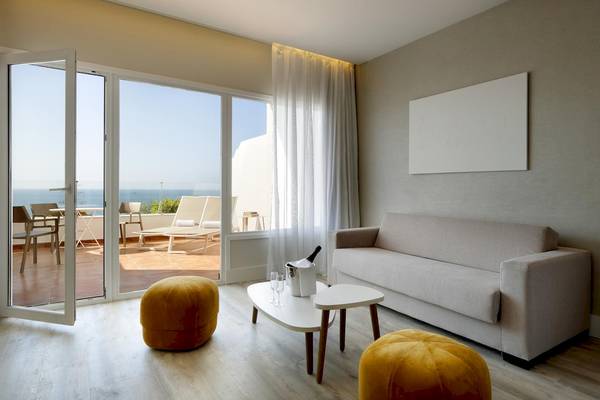 Wohnzimmer mit Meerblick im Playabonita Hotel mit Couch, Tisch und großen Fenstern.