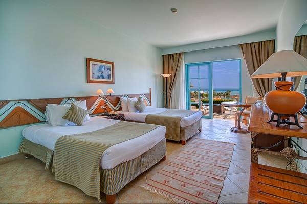 Hotelzimmer im The Chedi El Gouna mit zwei Betten, Meerblick und modernen Möbeln.