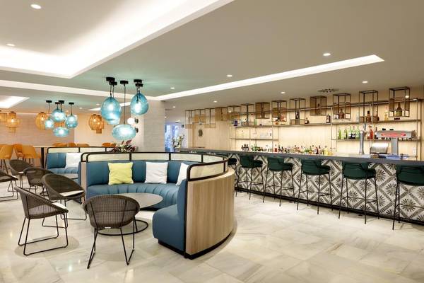 Die Bar-Lounge im Playabonita Hotel mit blauen Sitzbereichen und grünen Hockern.