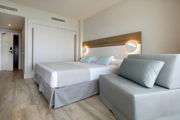 Schlafzimmer im Playabonita Hotel mit Doppelbett, grauen Kissen und hellem Holzboden.
