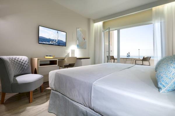 Innenansicht eines Zimmers im Playabonita Hotel mit Bett, Schreibtisch und Fernseher.