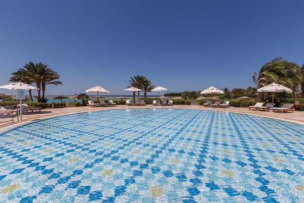 Außenbereich des Chedi El Gouna Hotels mit Swimmingpool, Sonnenliegen und Sonnenhuten