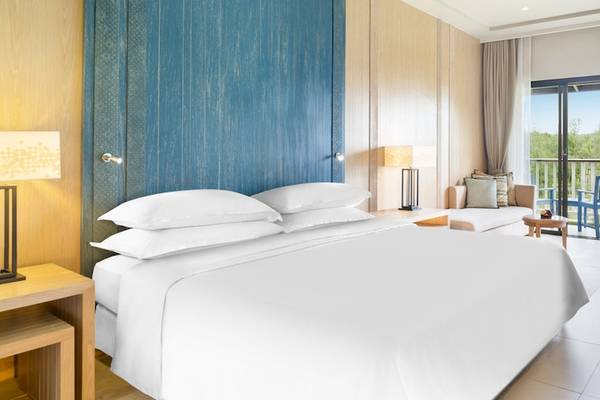 Ein modernes Hotelzimmer im Dusit Thani Krabi Beach Resort mit einem großen Bett, Balkon und Aussicht.