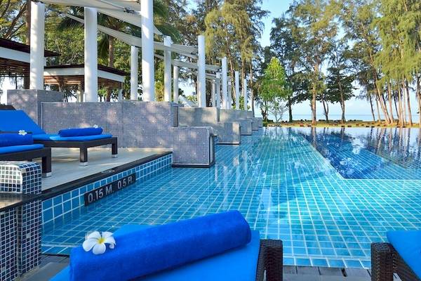 Infinity-Pool des Dusit Thani Krabi Beach Resort mit blauen Liegen und Blumen.