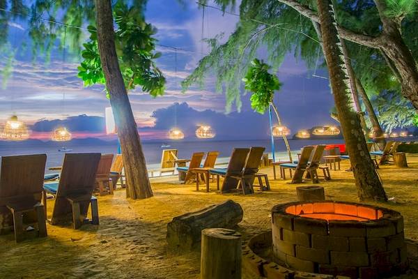 Außenbereich des Dusit Thani Krabi Beach Resort bei Sonnenuntergang mit Strand, Bäumen und Meerblick.