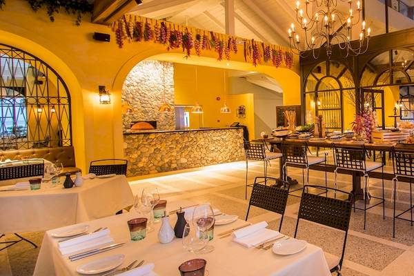Innenansicht des Restaurants im Dusit Thani Krabi Beach Resort mit gelben Wänden, einem langen Tisch und gedeckten Tischen.