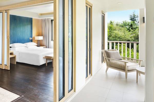 Zimmer im Dusit Thani Krabi Beach Resort mit Blick auf den Balkon und die Natur.