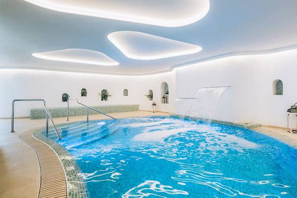 Ein Hallenbad im Iberostar Selection Fuerteventura Palace mit Wasserfall und modernen Beleuchtungselementen.