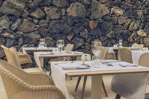 Innenansicht des Restaurants im Iberostar Selection Fuerteventura Palace mit Steinwand und gedeckten Tischen.