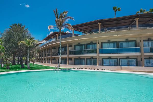 Außenansicht des Iberostar Selection Fuerteventura Palace Hotels mit Pool und tropischen Bäumen.