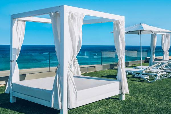 Poolside-Lounge-Bereich im Iberostar Selection Fuerteventura Palace mit weißen Liegen und Sonnenschirmen.
